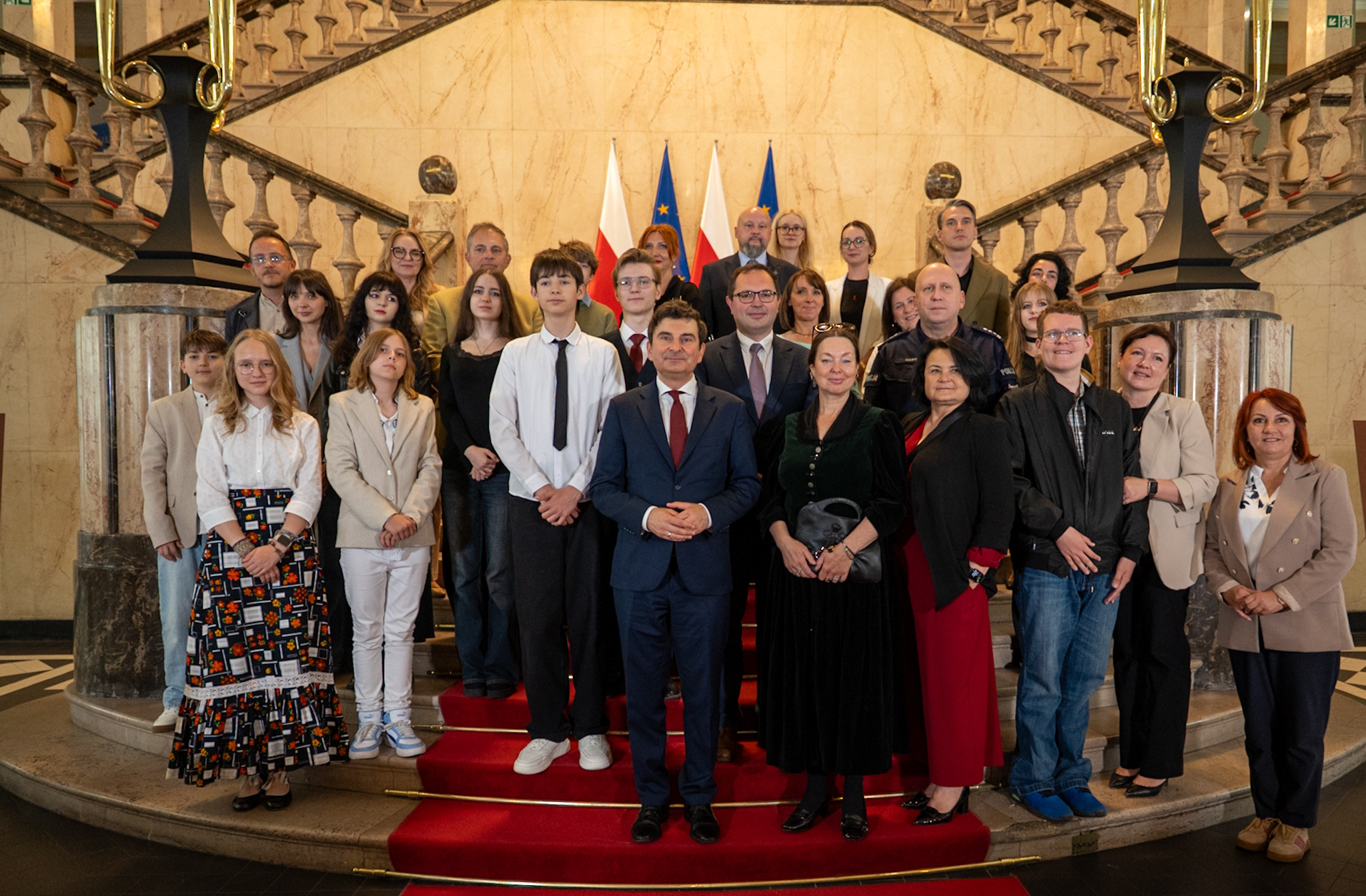 Zdjęcie grupowe uczestników wydarzenia na schodach westybulu.