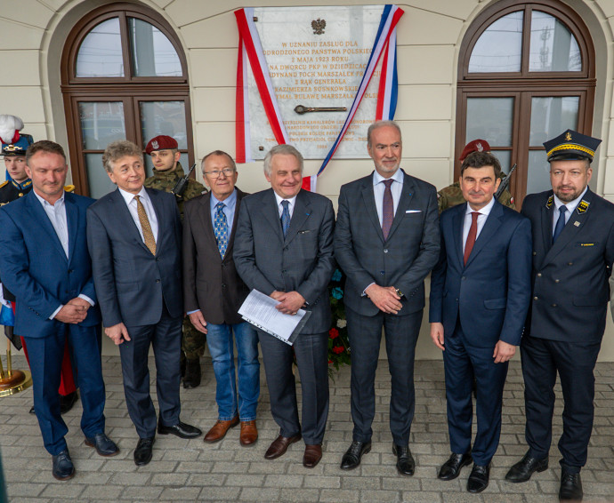 Zdjęcie uczestników wydarzenia przed tablicą pamiątkową.